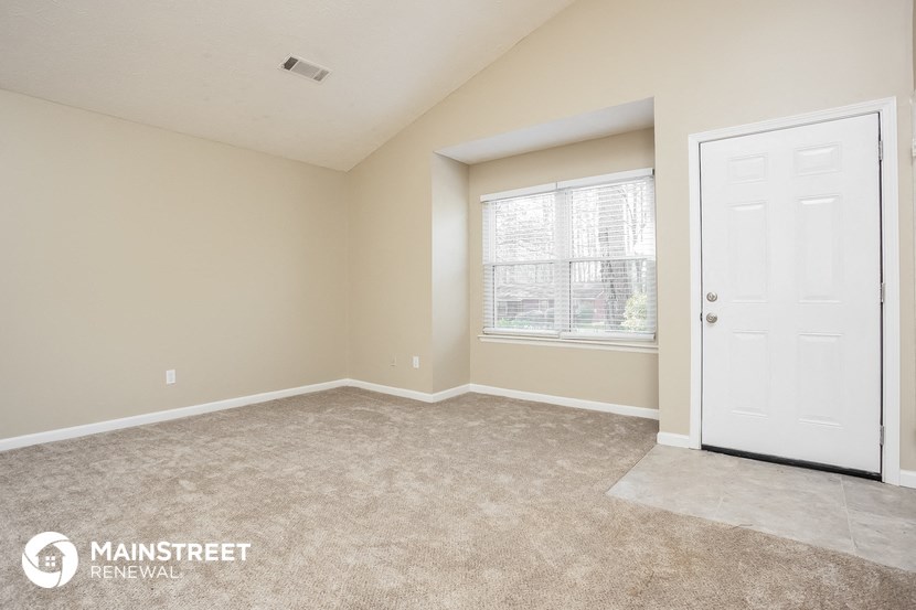the living room of a home with a white door and a window