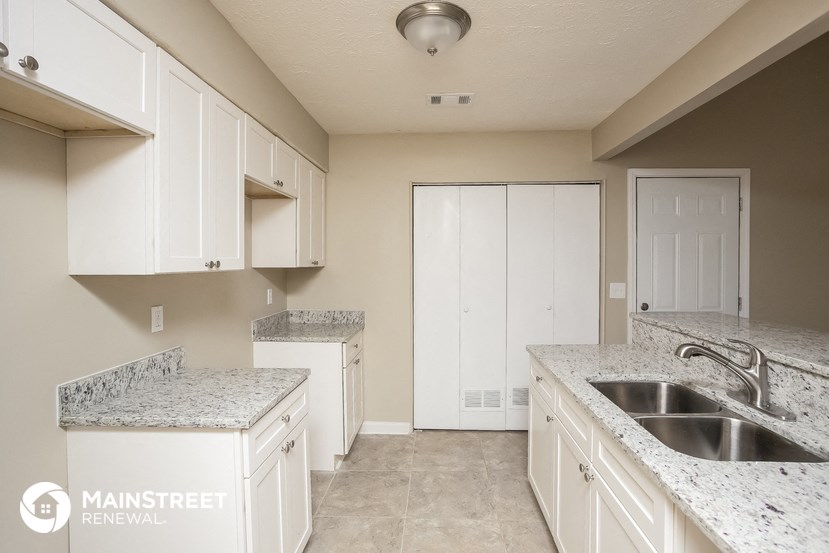 a kitchen with white cabinets and granite counter tops and a sink
