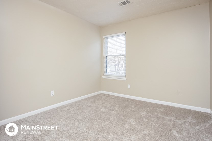 the upstairs bedroom has a carpeted floor and a window