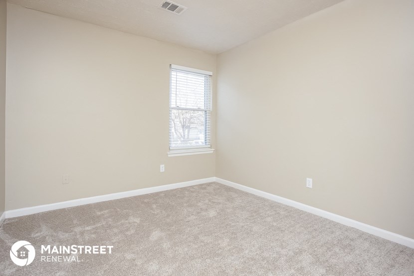 a bedroom with a carpeted floor and a window