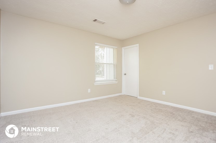 a bedroom with a carpeted floor and a window