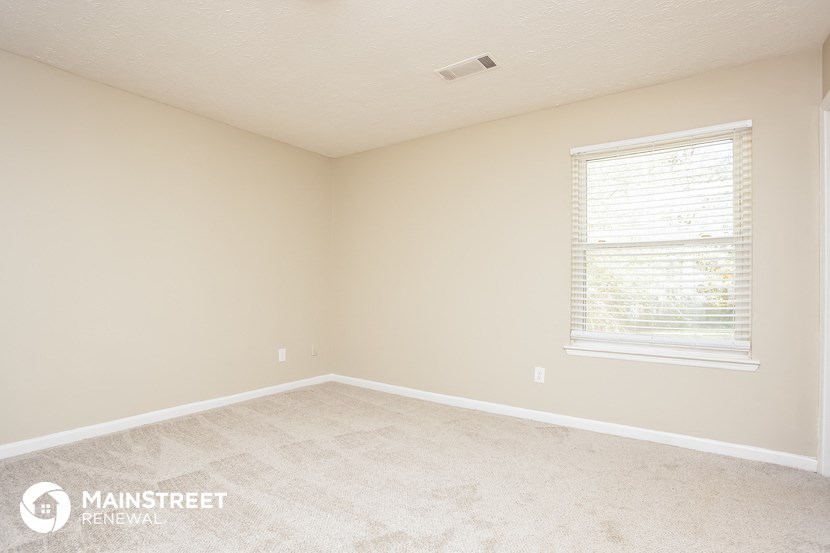 a bedroom with a large window and a carpeted floor