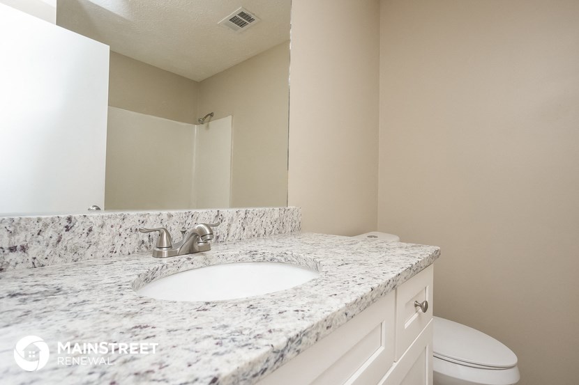 a bathroom with a marble counter top and a sink and a toilet