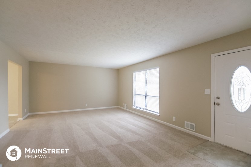 the spacious living room of a house with a white door