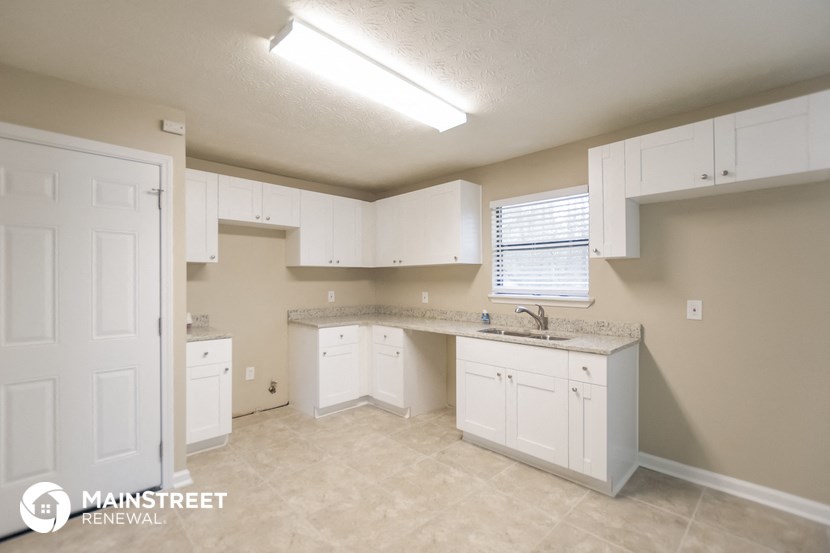 an empty kitchen with white cabinets and counters and a sink