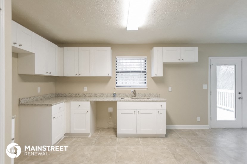 a kitchen with white cabinets and a sink and a window