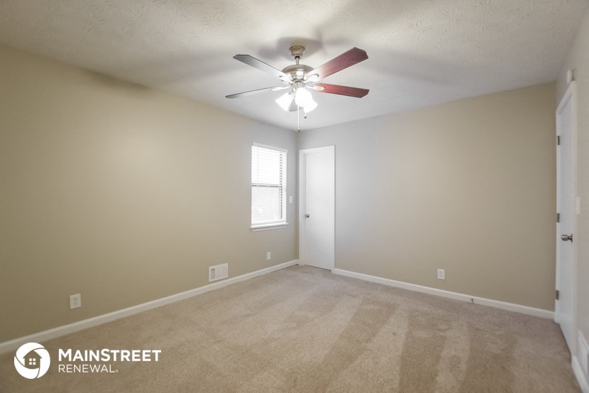 the spacious living room with carpet and a ceiling fan