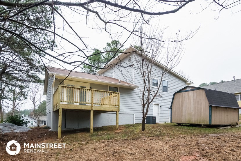 the back of a white house with a porch and a barn