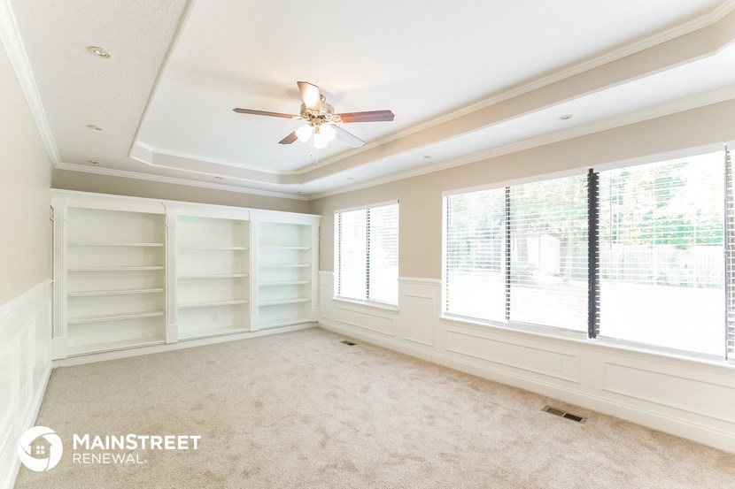 an empty room with white shelves and a ceiling fan