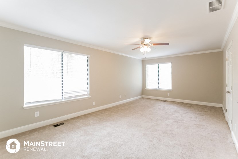 an empty room with a ceiling fan and two windows