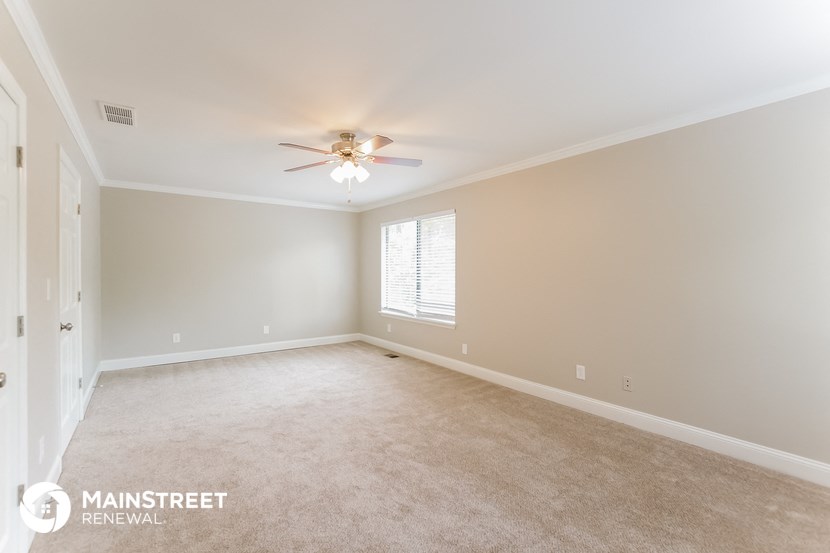 the spacious living room with ceiling fan and carpeting