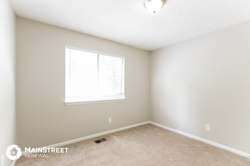 a bedroom with a large window and a carpeted floor