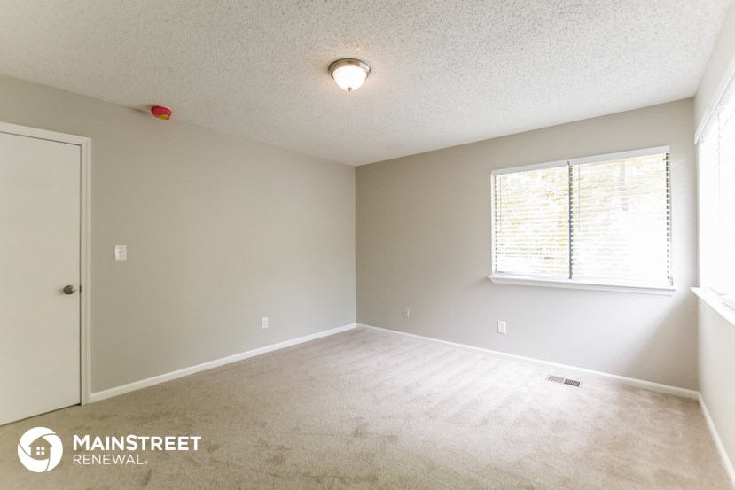 a spacious living room with a white carpet and a window