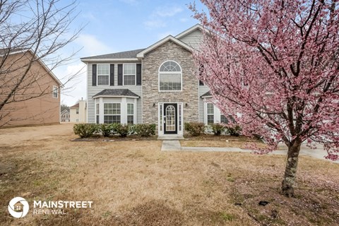 a home with a pink flowering tree in front of it