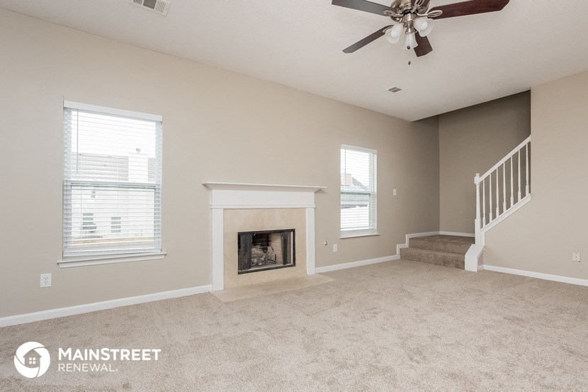 an empty living room with a fireplace and stairs