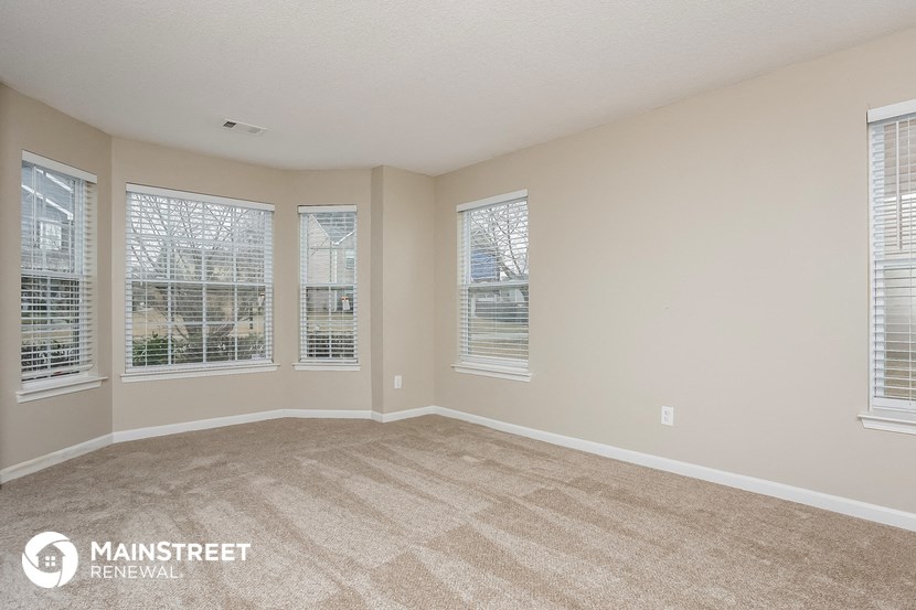 the living room of an apartment with carpet and windows