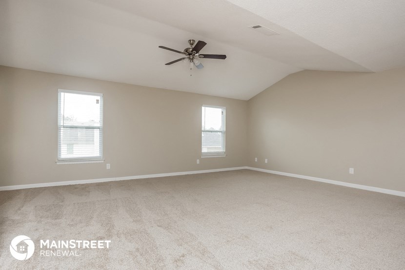 the spacious living room with carpeting and a ceiling fan
