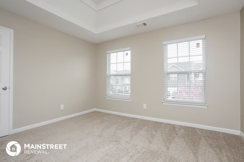 the living room of a new home with carpet and two windows