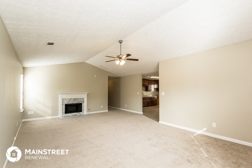 an empty living room with a fireplace and a ceiling fan