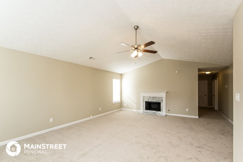 the spacious living room with fireplace and ceiling fan