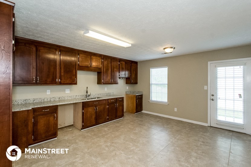 an empty kitchen with wooden cabinets and tile flooring
