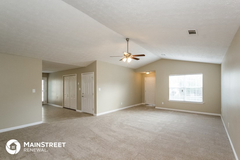 an empty living room with a ceiling fan