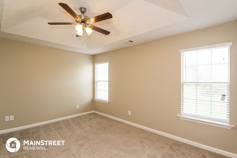 a living room with a ceiling fan and two windows