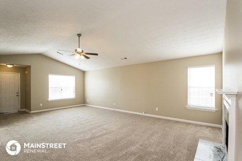 the spacious living room with carpet and ceiling fan