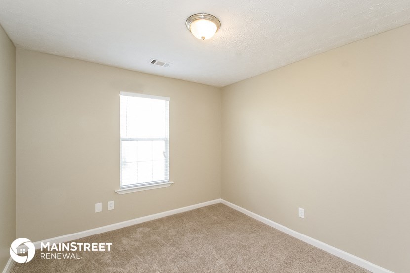 an empty bedroom with a window and carpeting