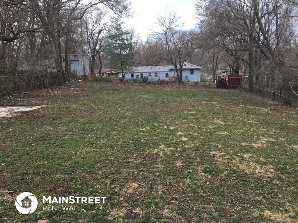 a large yard with a white house in the background