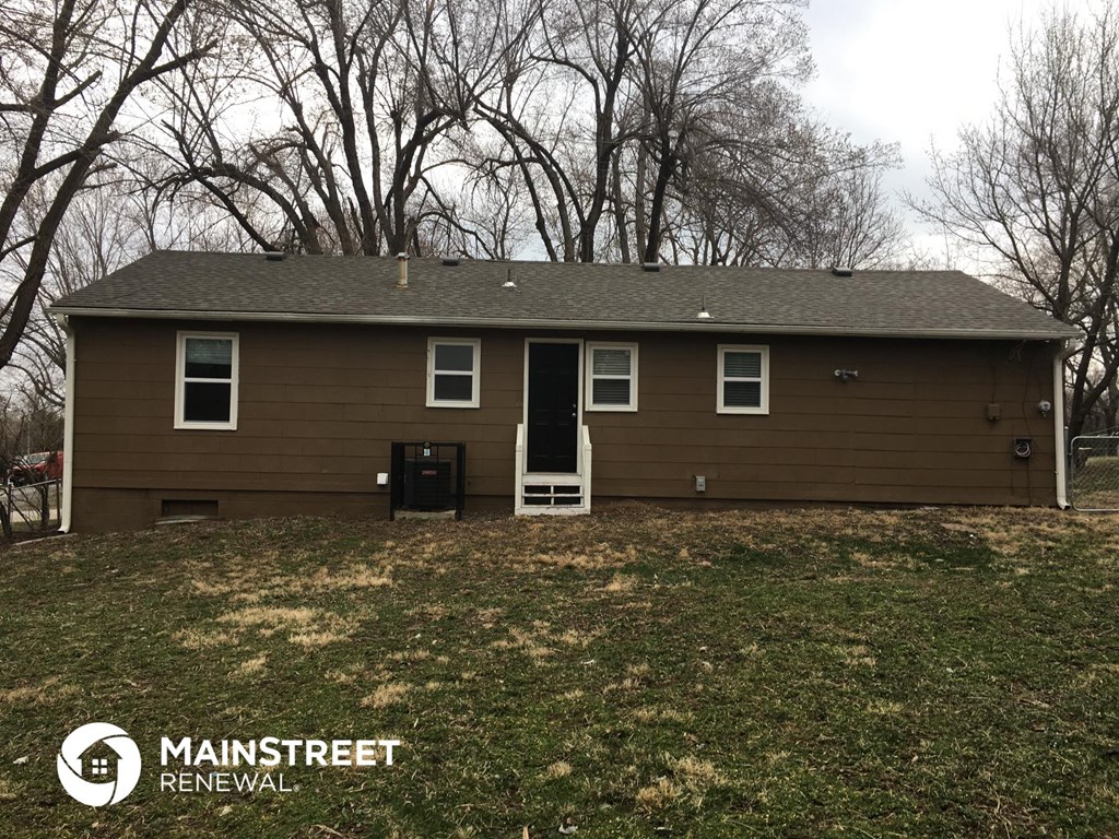 the front of a brown house with trees in the background