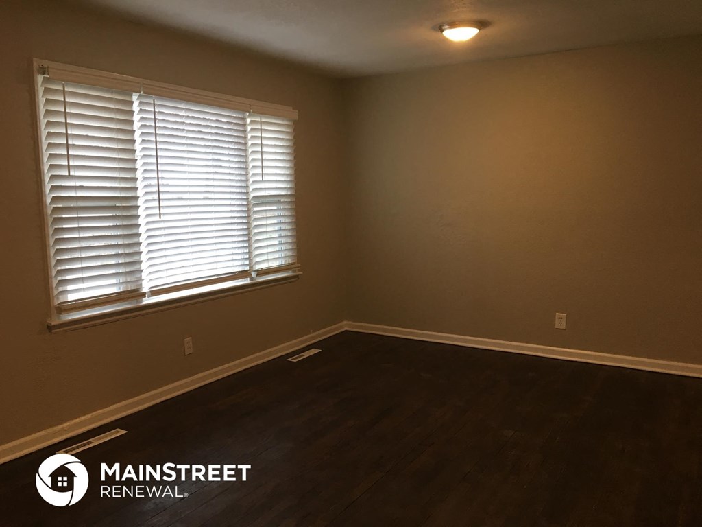 the living room of a house with wood floors and a window