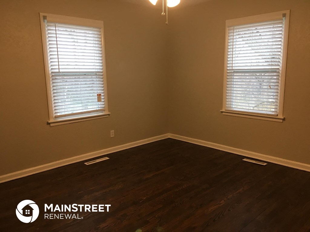 a living room with wood floors and two windows