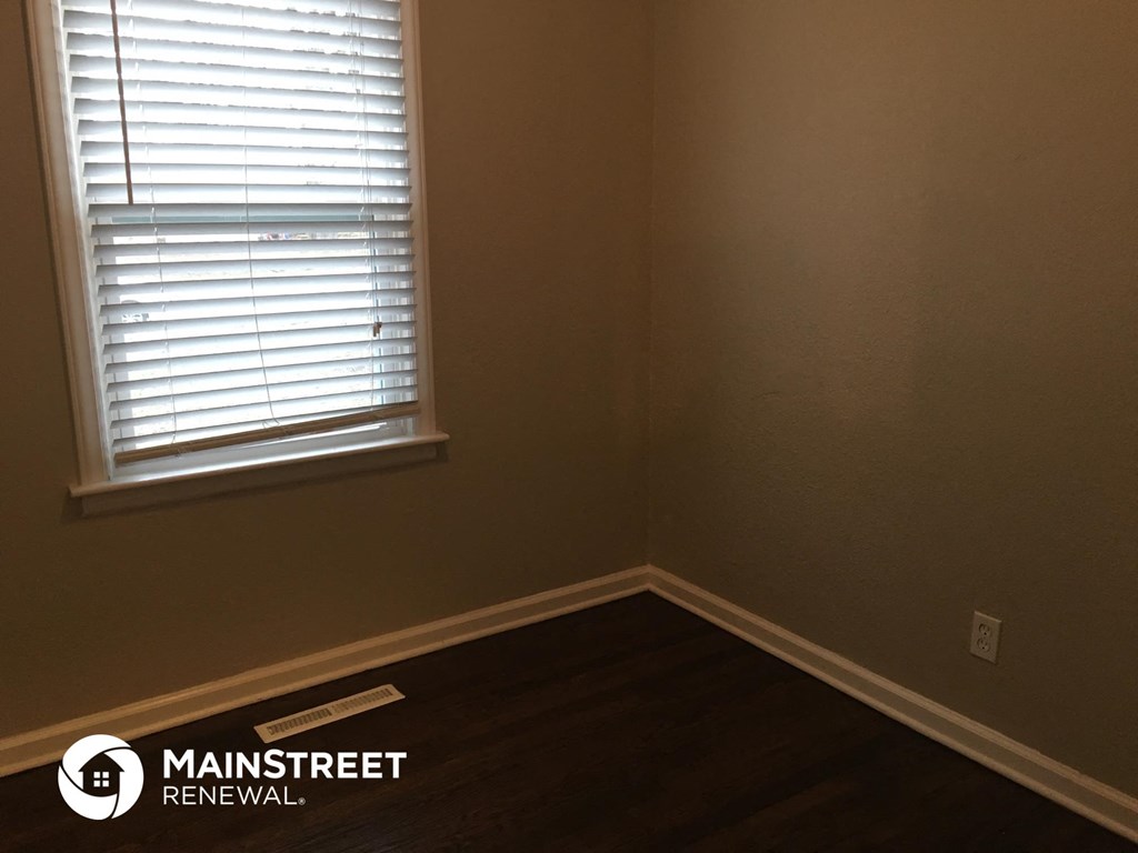 the corner of a room with a window and wooden floors