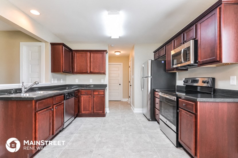 a kitchen with wood cabinets and black counter tops and a black stove and refrigerator