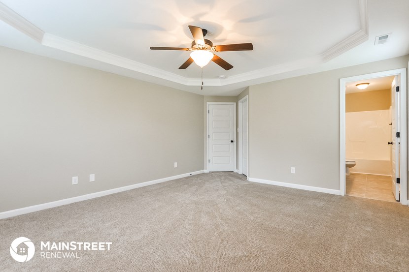 the spacious living room with ceiling fan and carpeting