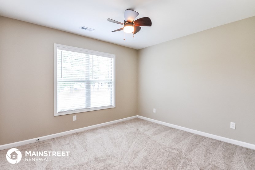 the master bedroom has a carpeted floor and a ceiling fan