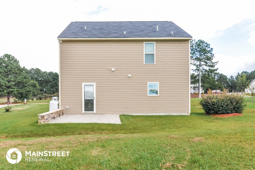 the front of a small house with a yard and a driveway