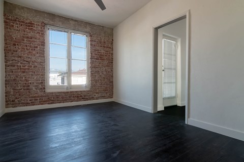 an empty living room with a brick wall and a window