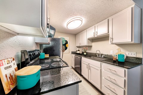a kitchen with black counter tops and white cabinets