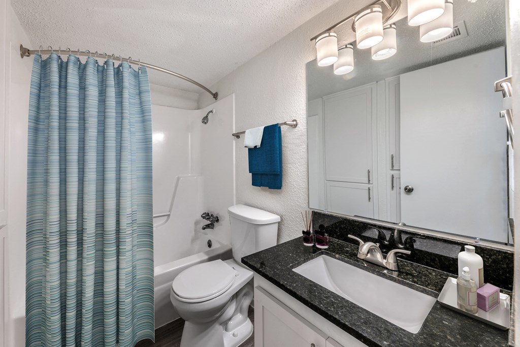 a white bathroom with a blue shower curtain and a white toilet and sink