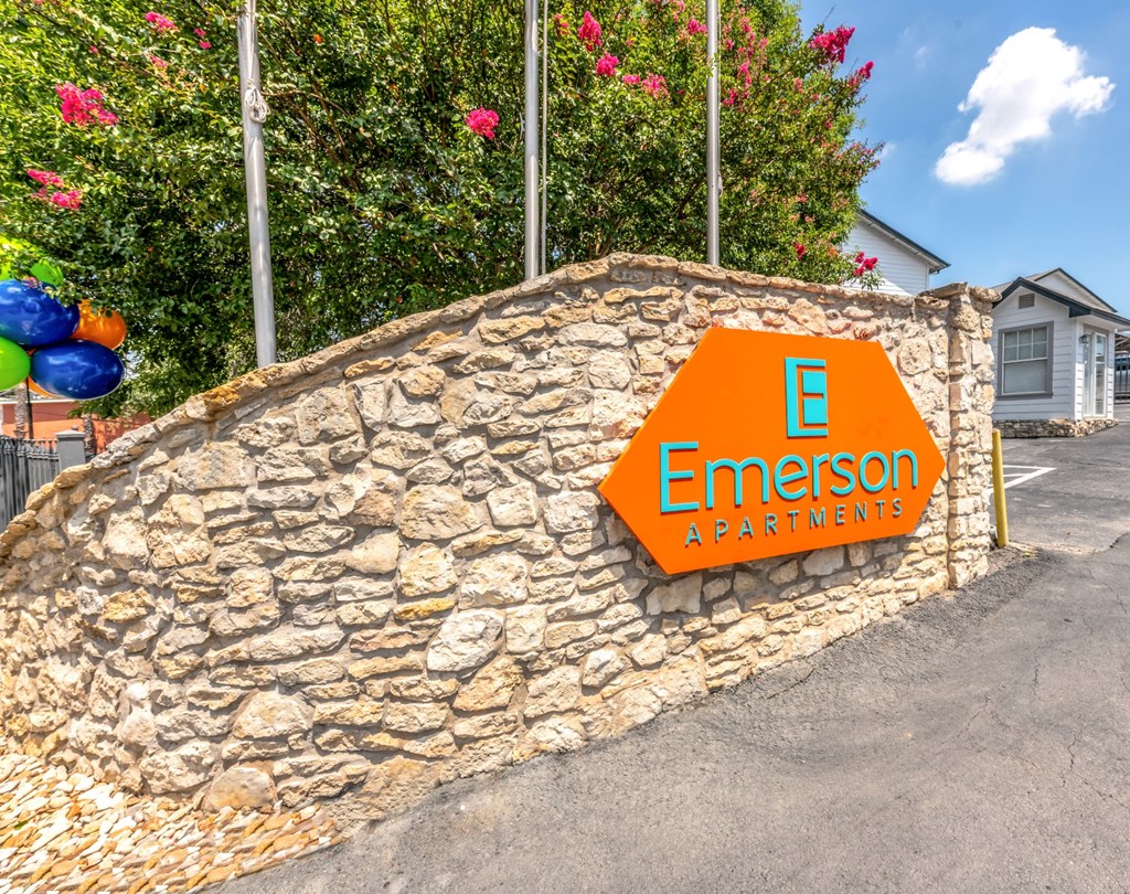 a stone retaining wall with an orange sign that reads e emerson apartments