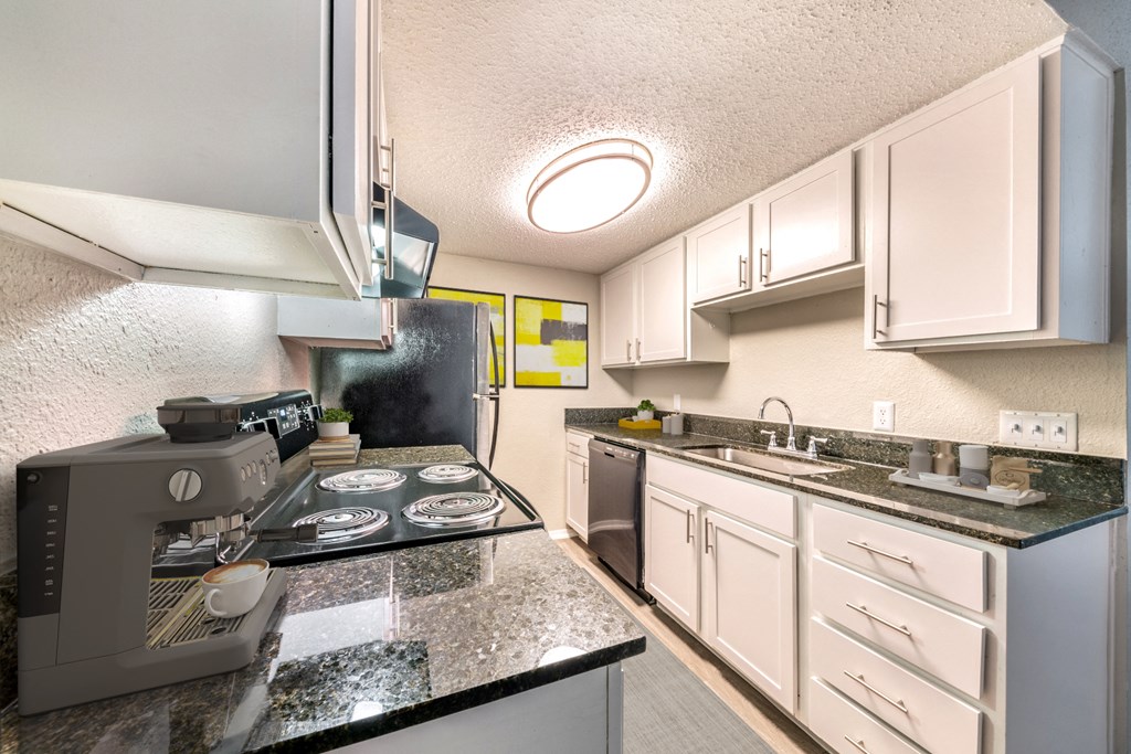 a kitchen with white cabinets and granite counter tops and a stove and sink