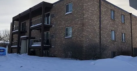 A brick building with a balcony and snow on the ground.