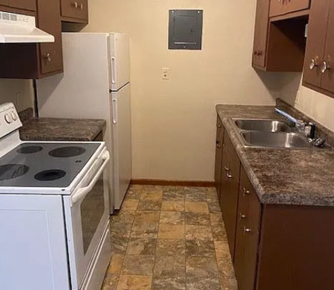 A kitchen with a white stove top oven and a white refrigerator.