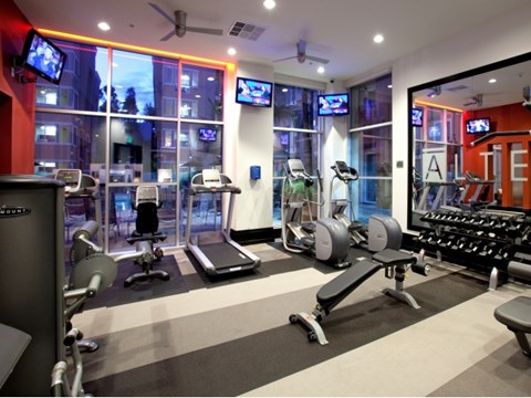A gym with a variety of equipment including treadmills, weights, and exercise machines.