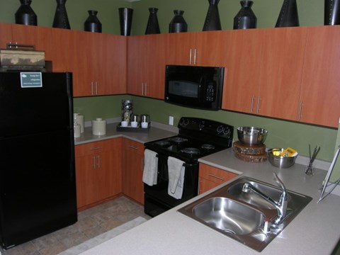 A kitchen with a black refrigerator, black stove, and black microwave.