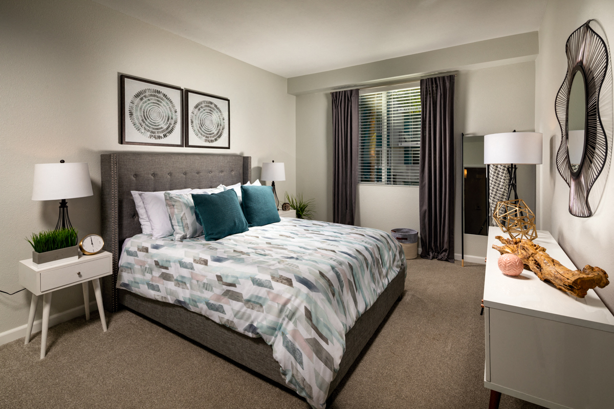 A bedroom with a large bed and a nightstand with a lamp.