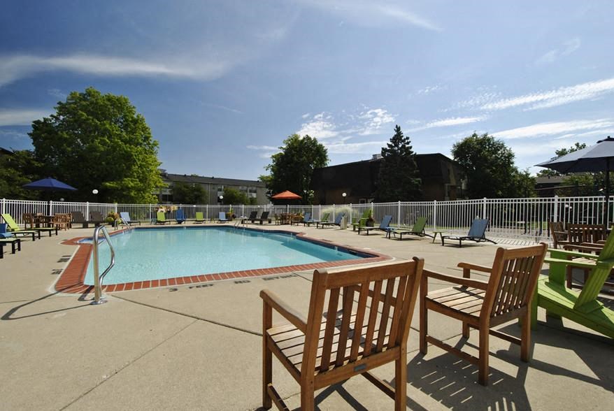 a swimming pool with wooden benches and chairs around it