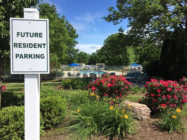 a sign in front of a park with flowers